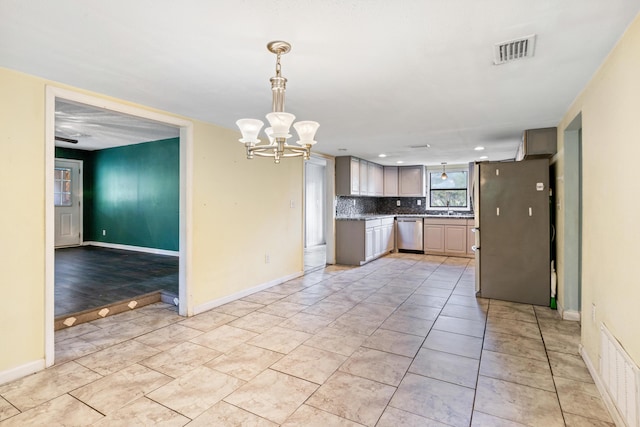 kitchen with sink, decorative backsplash, appliances with stainless steel finishes, decorative light fixtures, and a chandelier