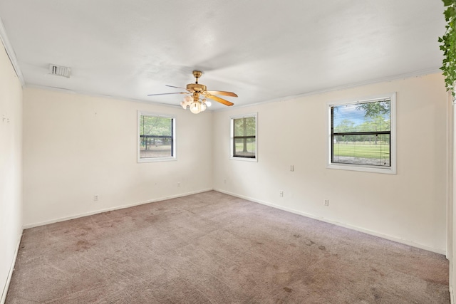 spare room with ceiling fan, crown molding, and light colored carpet