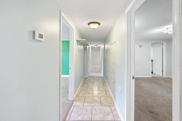 hallway with light colored carpet and a textured ceiling