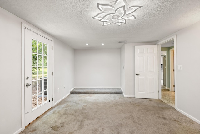 carpeted empty room with a textured ceiling and an inviting chandelier