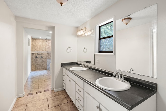 bathroom featuring vanity, a shower, and a textured ceiling