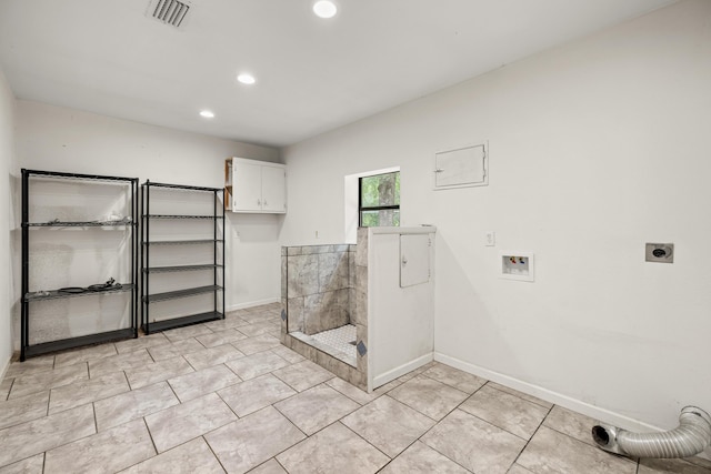 clothes washing area with electric dryer hookup, cabinets, light tile patterned floors, and washer hookup