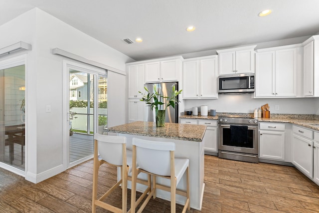 kitchen with white cabinetry, light hardwood / wood-style floors, a kitchen island, stainless steel appliances, and light stone counters