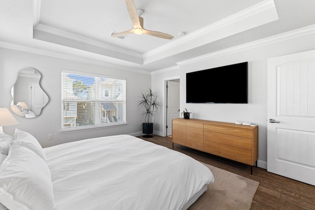 bedroom featuring dark wood-type flooring, ceiling fan, ornamental molding, and a tray ceiling