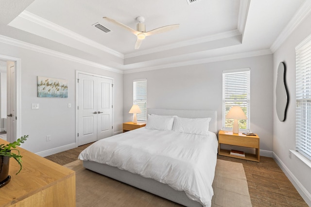 bedroom featuring ceiling fan, a raised ceiling, crown molding, and wood-type flooring