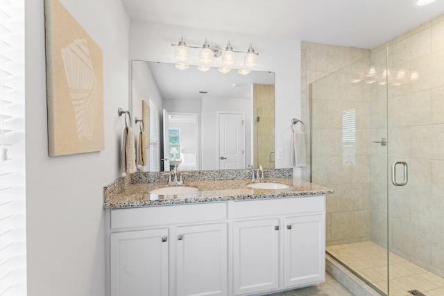 bathroom with an enclosed shower and dual vanity