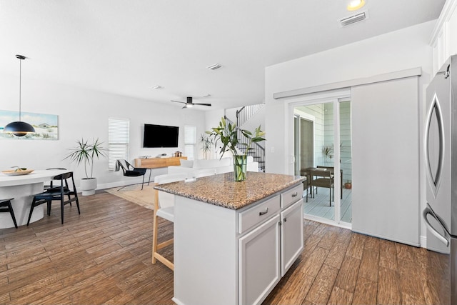 kitchen featuring a kitchen island, white cabinets, dark hardwood / wood-style floors, pendant lighting, and ceiling fan