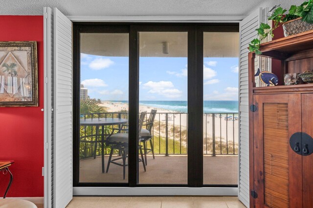 entryway featuring a beach view, a water view, plenty of natural light, and a textured ceiling