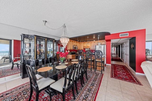 dining area with a chandelier, a textured ceiling, and light tile floors