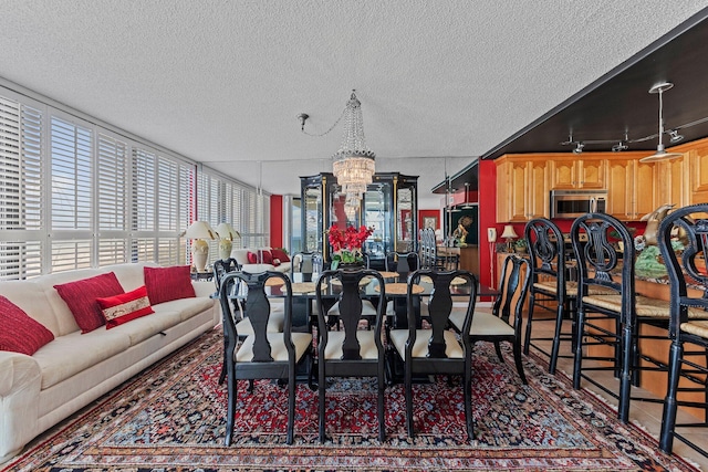 dining space featuring a chandelier, a textured ceiling, and rail lighting