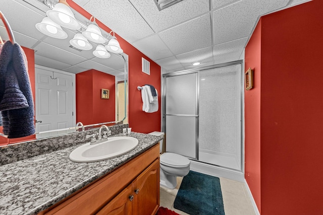 bathroom featuring tile flooring, a shower with shower door, oversized vanity, a drop ceiling, and toilet