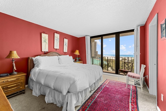 carpeted bedroom featuring a textured ceiling, a water view, and access to exterior