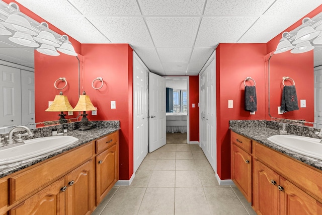 bathroom featuring dual bowl vanity, tile flooring, and a drop ceiling