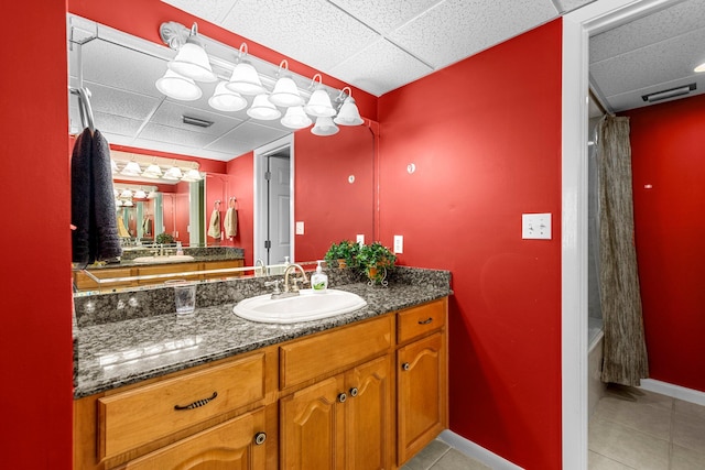 bathroom with tile flooring, a drop ceiling, and vanity