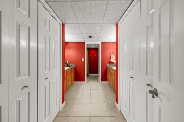 corridor with a paneled ceiling and light tile flooring