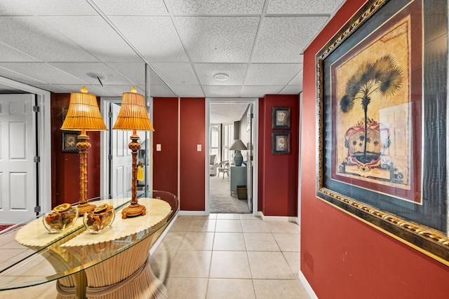 corridor with light tile flooring and a paneled ceiling