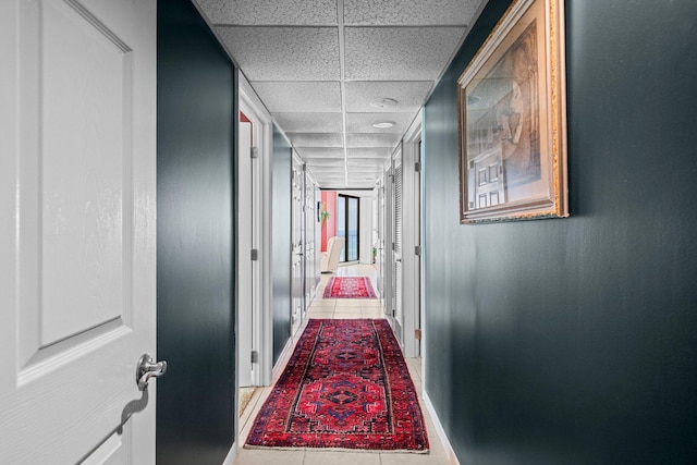 hall featuring tile floors and a drop ceiling