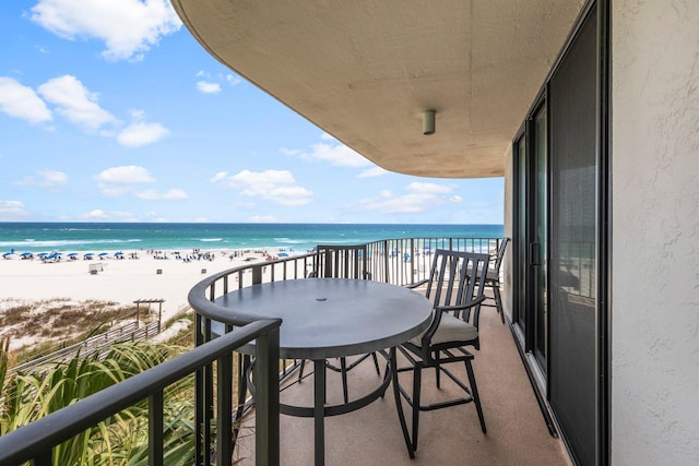 balcony with a water view and a view of the beach