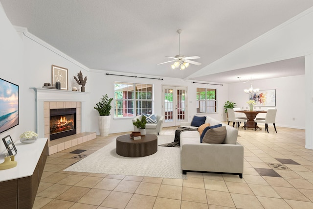 tiled living room with ceiling fan with notable chandelier, ornamental molding, a fireplace, and lofted ceiling