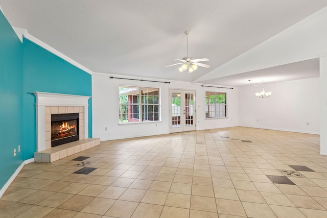 unfurnished living room with ceiling fan with notable chandelier, a tiled fireplace, light tile floors, and crown molding