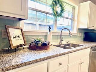 9720 Parker Lake Cir, Navarre, FL 32566 - kitchen with stainless steel dishwasher, tasteful backsplash, white cabinets, light stone counters, and a sink