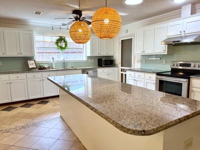 9720 Parker Lake Cir, Navarre, FL 32566 - kitchen featuring ornamental molding, light tile patterned floors, white cabinets, under cabinet range hood, and appliances with stainless steel finishes