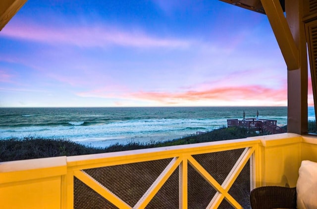 balcony at dusk with a water view and a beach view