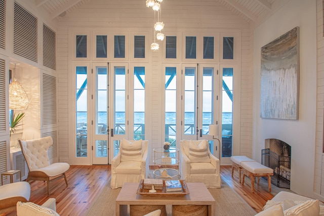 living room featuring a healthy amount of sunlight, a water view, light hardwood / wood-style flooring, and beamed ceiling