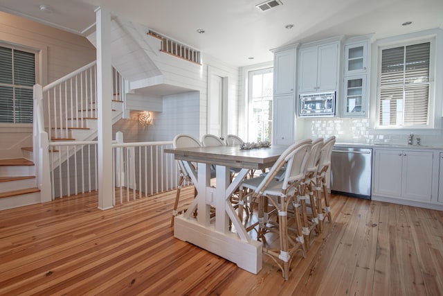 kitchen with white cabinets, backsplash, stainless steel appliances, light wood-type flooring, and sink