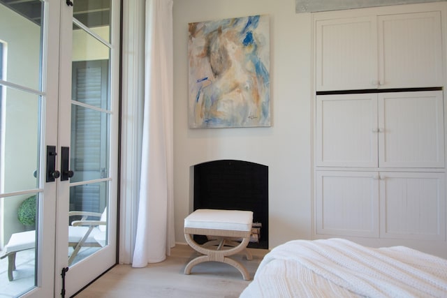 bedroom featuring multiple windows, light wood-type flooring, french doors, and access to exterior