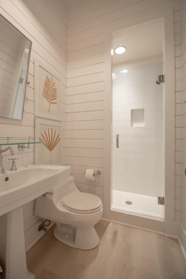 bathroom featuring hardwood / wood-style flooring, a shower with shower door, and toilet