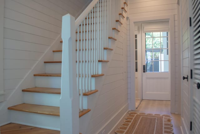 entryway with light hardwood / wood-style floors and wooden walls