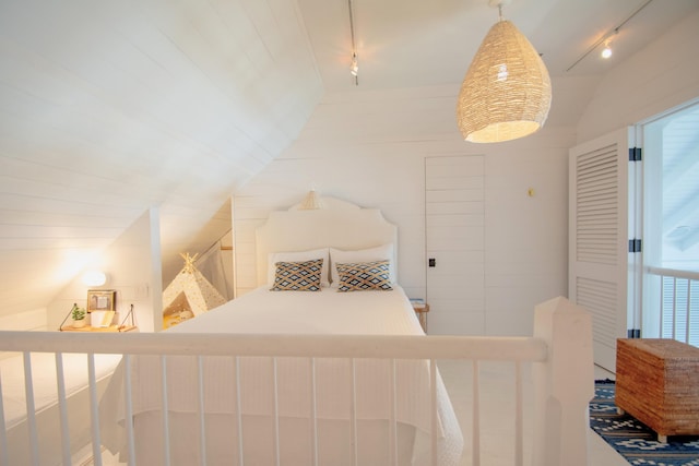 bedroom with rail lighting and lofted ceiling