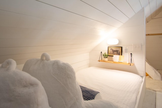 bedroom featuring wooden walls and vaulted ceiling