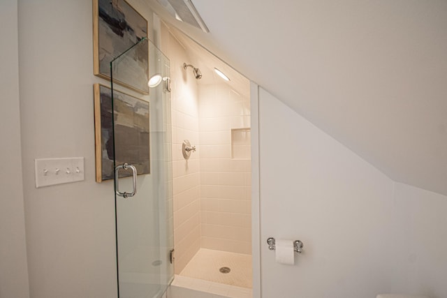 bathroom featuring lofted ceiling and a shower with shower door