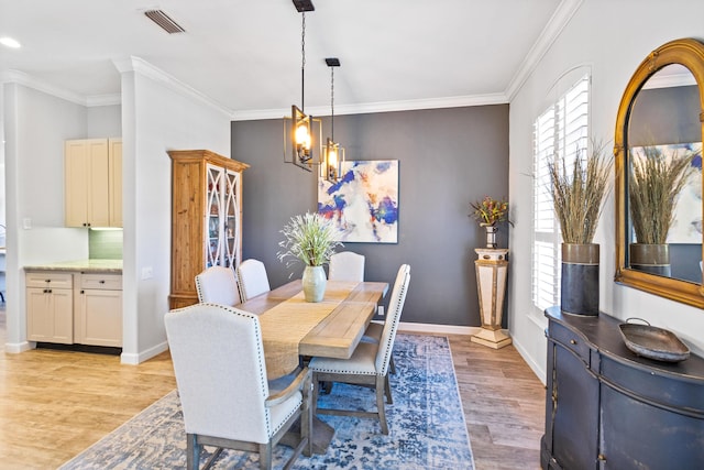 dining space featuring ornamental molding, light wood-type flooring, and an inviting chandelier