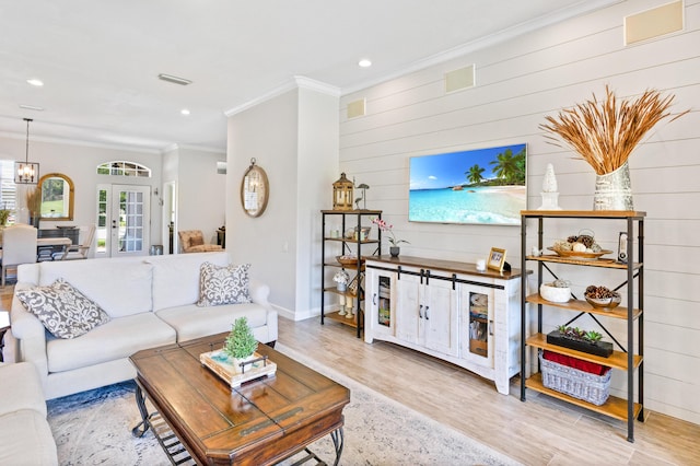 living room featuring crown molding, light hardwood / wood-style flooring, french doors, and wooden walls