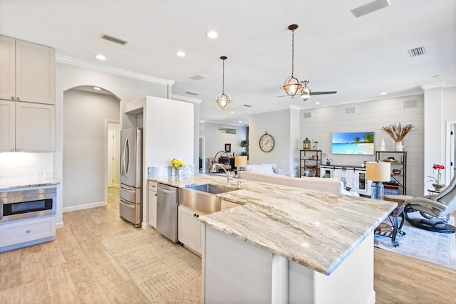 kitchen featuring white cabinetry, stainless steel appliances, decorative light fixtures, and light wood-type flooring