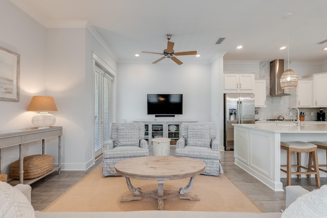 living room with light hardwood / wood-style floors, ornamental molding, and ceiling fan