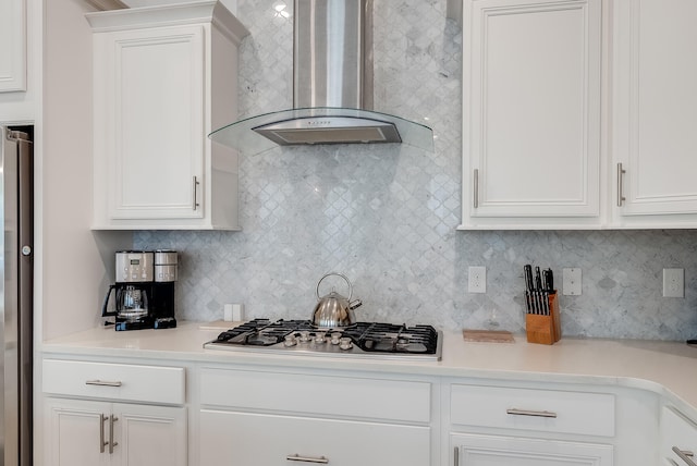 kitchen featuring wall chimney range hood, tasteful backsplash, white cabinetry, and stainless steel appliances