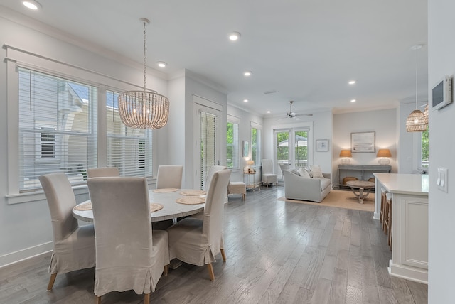 dining space with crown molding, wood-type flooring, and ceiling fan with notable chandelier