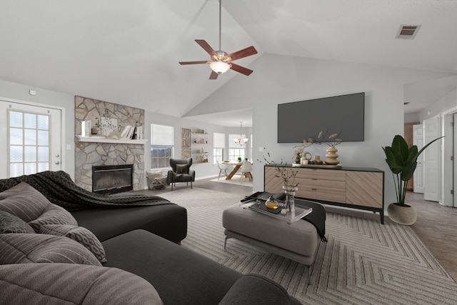 living room with a fireplace, plenty of natural light, high vaulted ceiling, and ceiling fan with notable chandelier