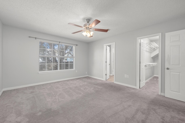 unfurnished bedroom with ceiling fan, a spacious closet, light carpet, and a closet