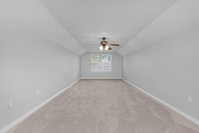 additional living space with a textured ceiling, light carpet, ceiling fan, and vaulted ceiling