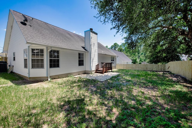 back of house with central AC unit, a wooden deck, and a lawn