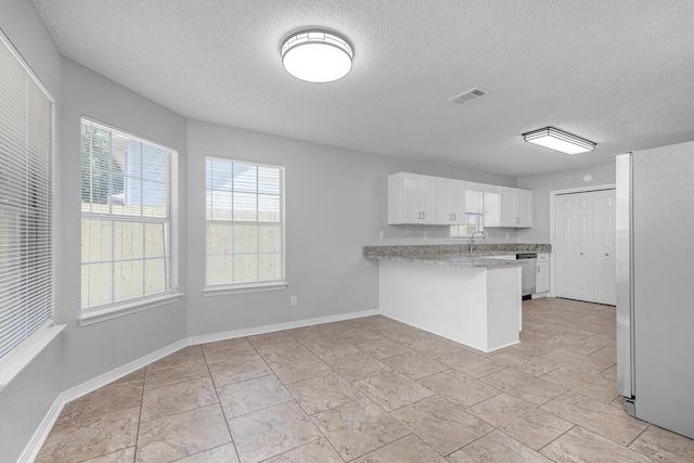 kitchen with kitchen peninsula, a textured ceiling, sink, white fridge, and white cabinetry