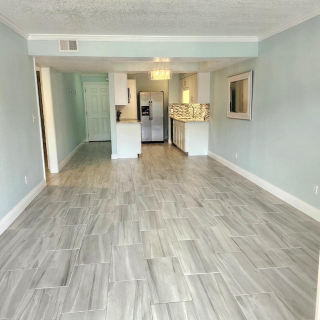 unfurnished living room with a textured ceiling and ornamental molding