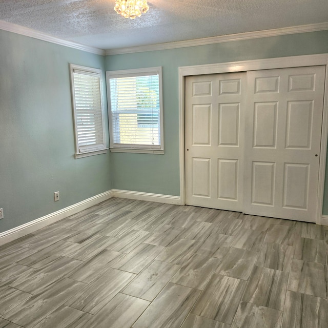 unfurnished bedroom featuring an inviting chandelier, light hardwood / wood-style flooring, ornamental molding, a textured ceiling, and a closet