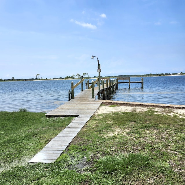 view of dock featuring a water view and a yard