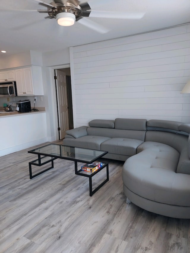 living area featuring light wood-style floors and a ceiling fan